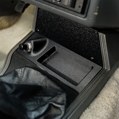 Car console with a black compartment and gear shift area.