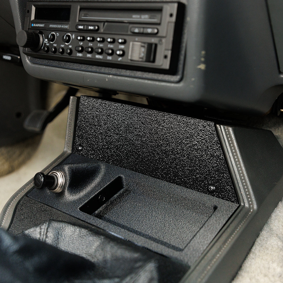 Car console with a CD player and open glove compartment.