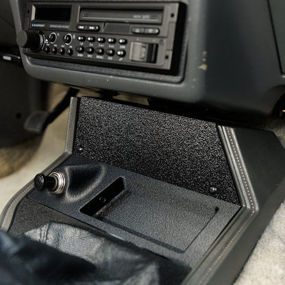 Car console with a CD player and open glove compartment.
